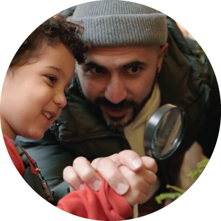 A father and son look at something through hand lens