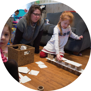 A girl begins to build a pyramid out of cardboard cylinders and cards
