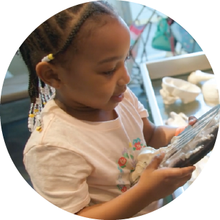 Girl examining a rock near a skeleton