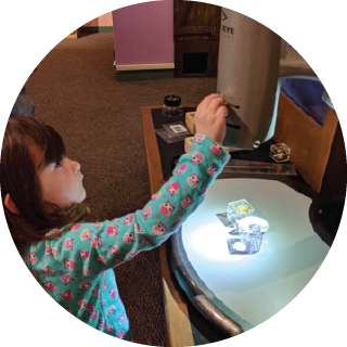 A girl uses a device to illuminate three translucent objects