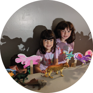 two girls use hand-made paper puppets to create shadows
