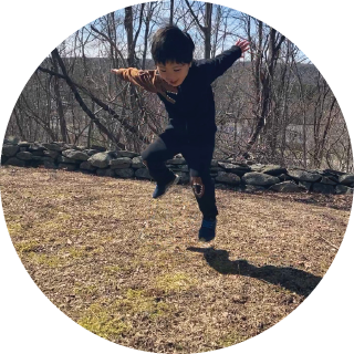a boy dances outside and looks at his shadow on the grass