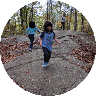 Two kids run over a rocky surface