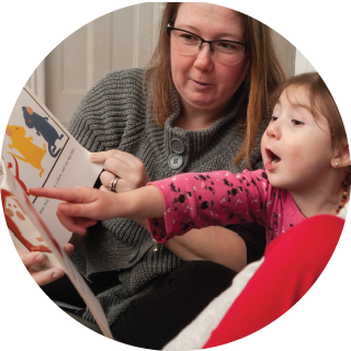 A girl excitedly points at a book and exclaims something.