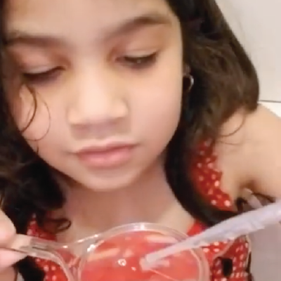 A preschooler and his school-age sister explore water drops in the tub