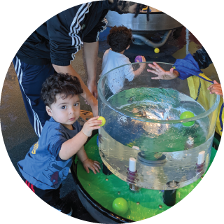 A child holds a ball near a water tank