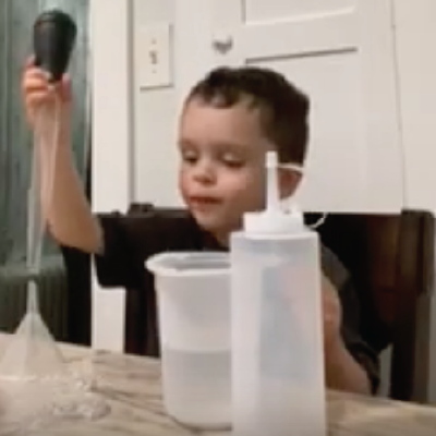A family moves water together with plastic cups and bottles of different sizes, a funnel, and a baster