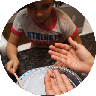 Boy examining small worms on a plate; a pair of hands holding worms
