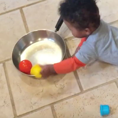 Infant makes sounds with balls and a pan